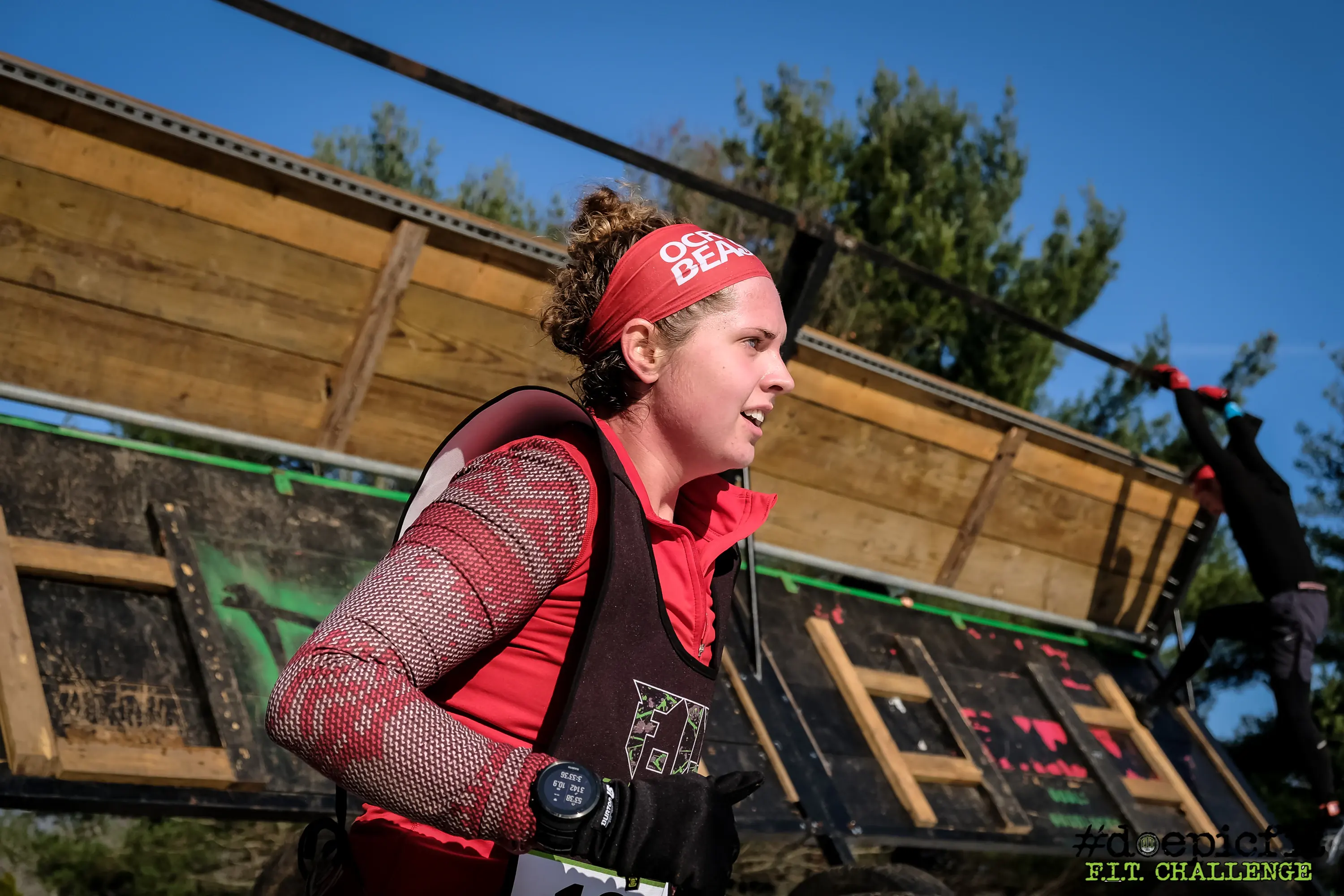 Kristina Petit in a red headband hauling herself along an obstacle at the F.I.T. Challenge